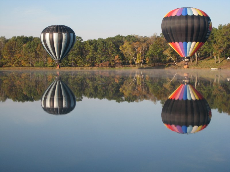 two hot air balloons touch down on a lake