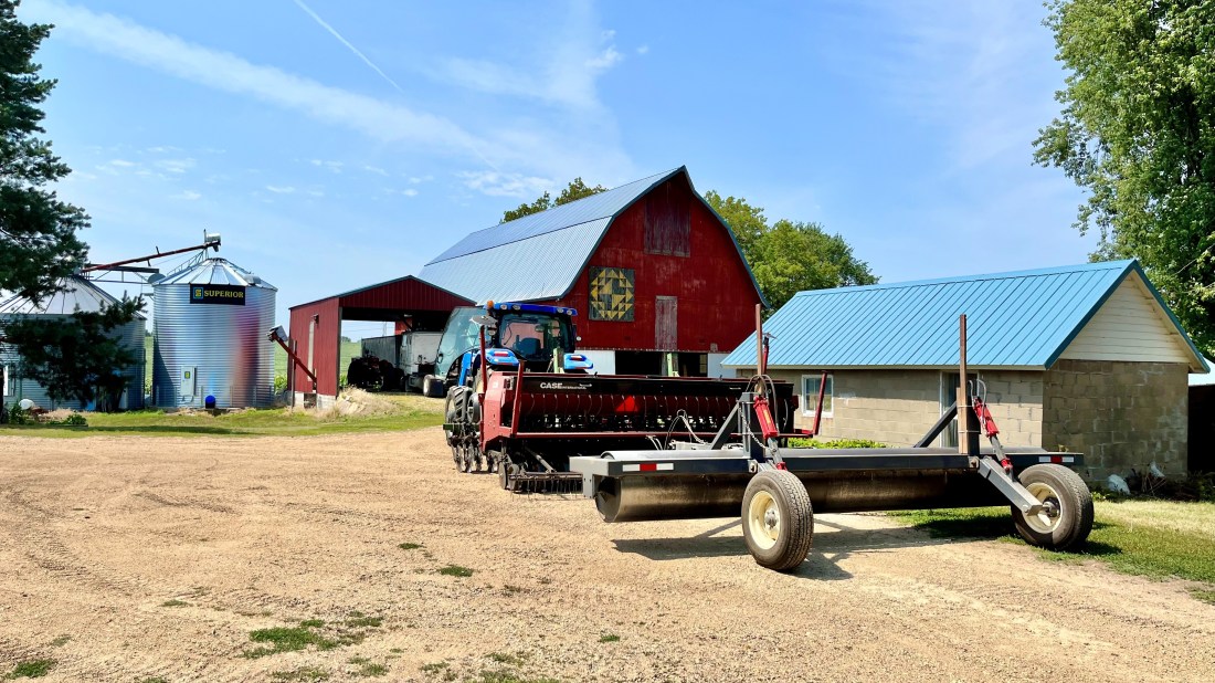 a barn and tractor with gravel and dirt parking area