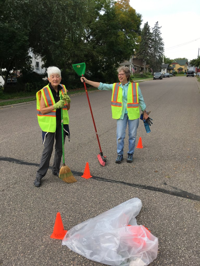 two women in safety vests with a rake